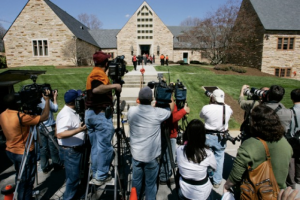 Members of the media photograph attendees of a memorial service after the Virginia Tech shooting. (Photo Credit: AP/Charles Dharapak)
