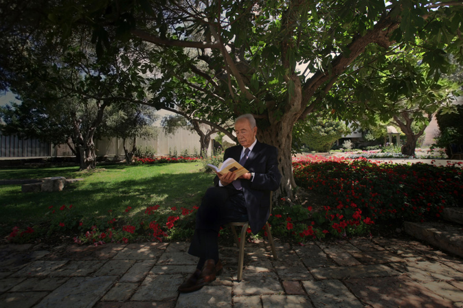 Peres reading at the presidential garden in Jerusalem in 2009. (NYT)
