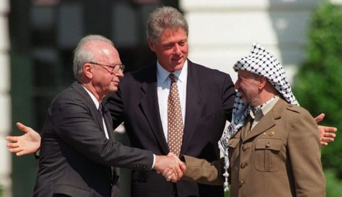 Israeli Prime Minister Yitzhak Rabin and PLO chairman Yasir Arafat shake hands with some encouragement by President Bill Clinton after signing the Oslo Accords in a ceremony hosted by the White House. (ABC)